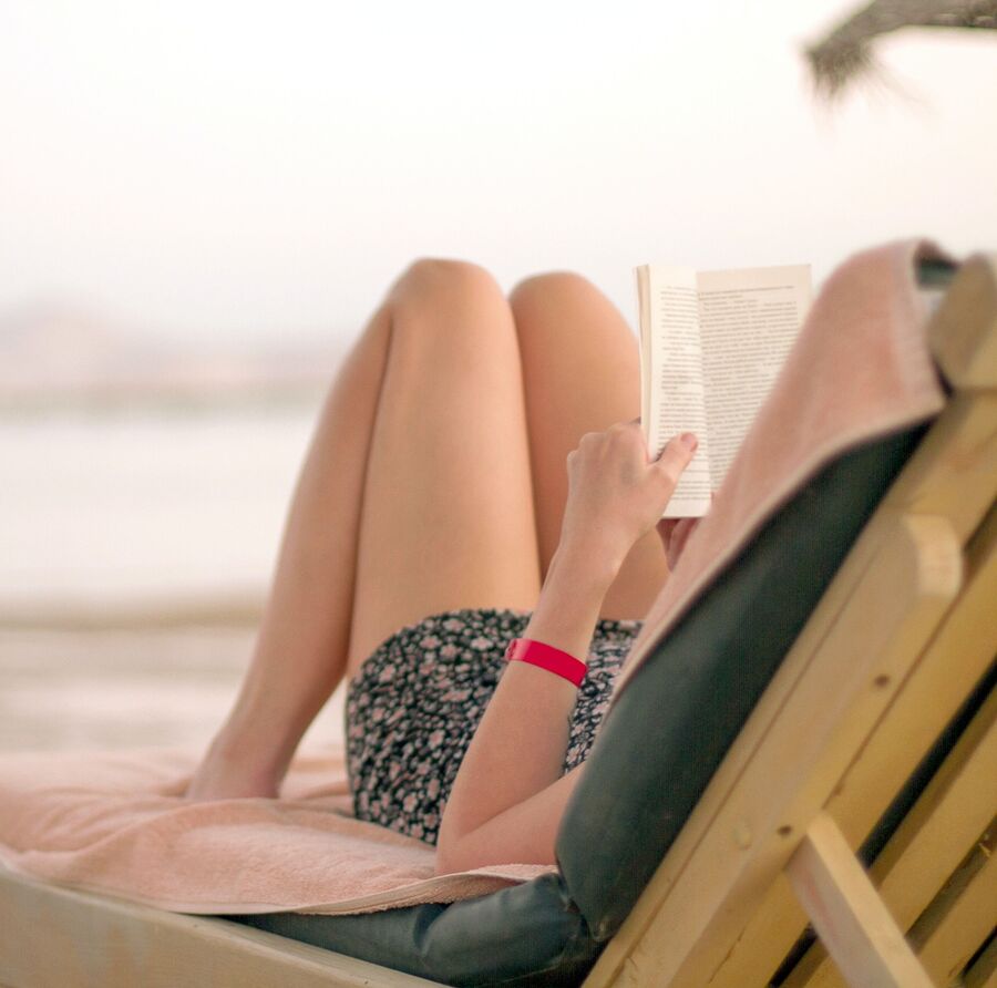 Billede af kvinde der læser på en strand