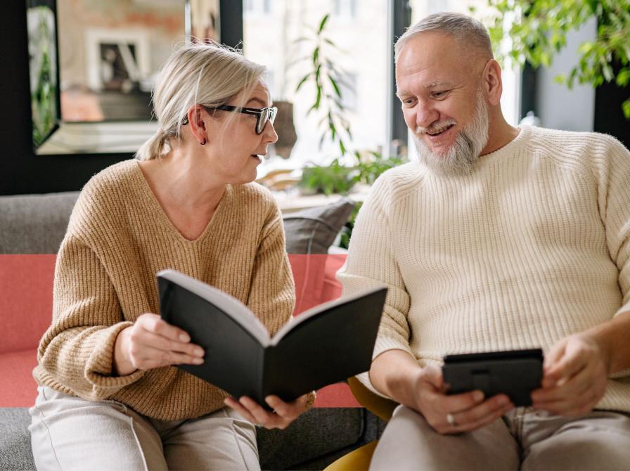 En kvinde viser sin mand en side fra en bog, mens de sidder i sofaen. 